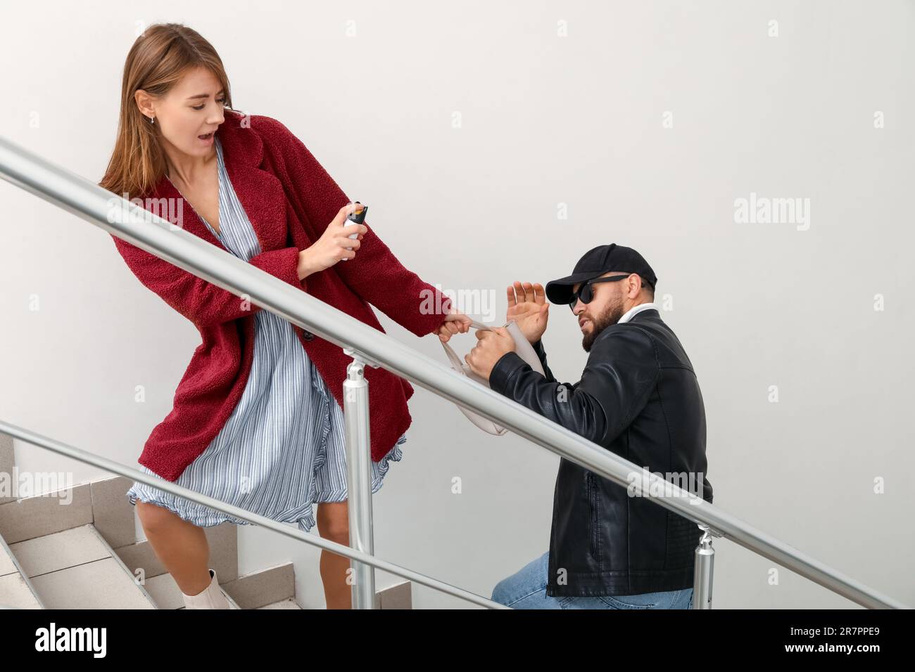 Young woman with pepper spray defending herself against thief in