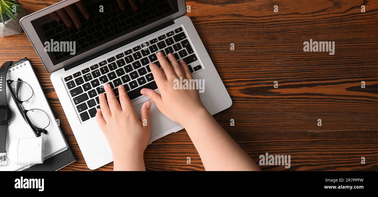 Female programmer using laptop at wooden table, top view Stock Photo