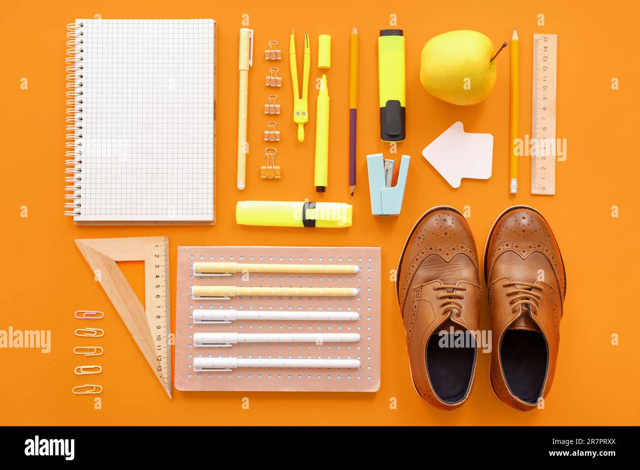 Cute shoes with fresh apple and different stationery on orange background Stock Photo