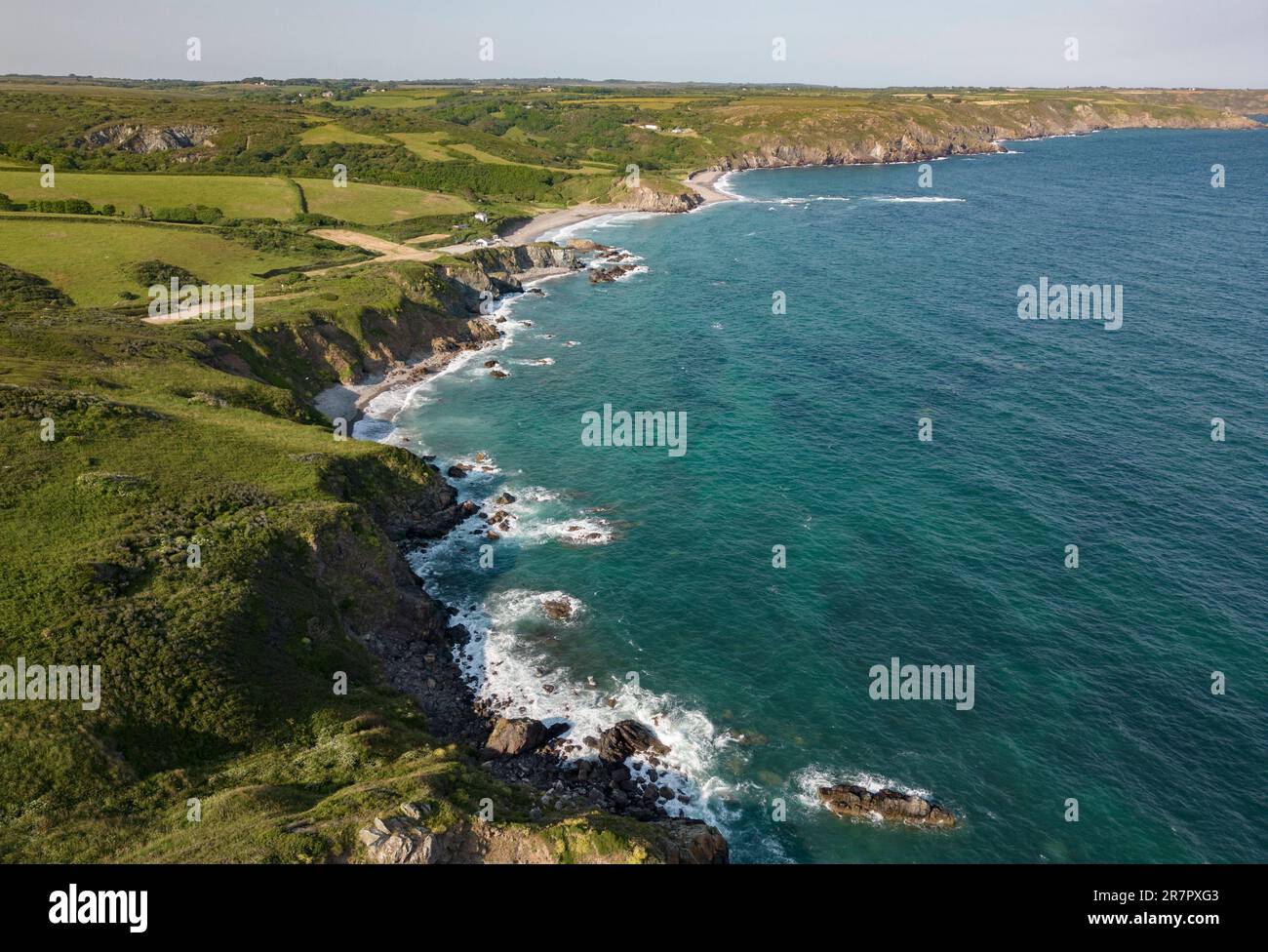 Aerial view of the rugged south Cornwall coastline near the village of Kuggar with the clear ocean breaking on the rocks. Stock Photo