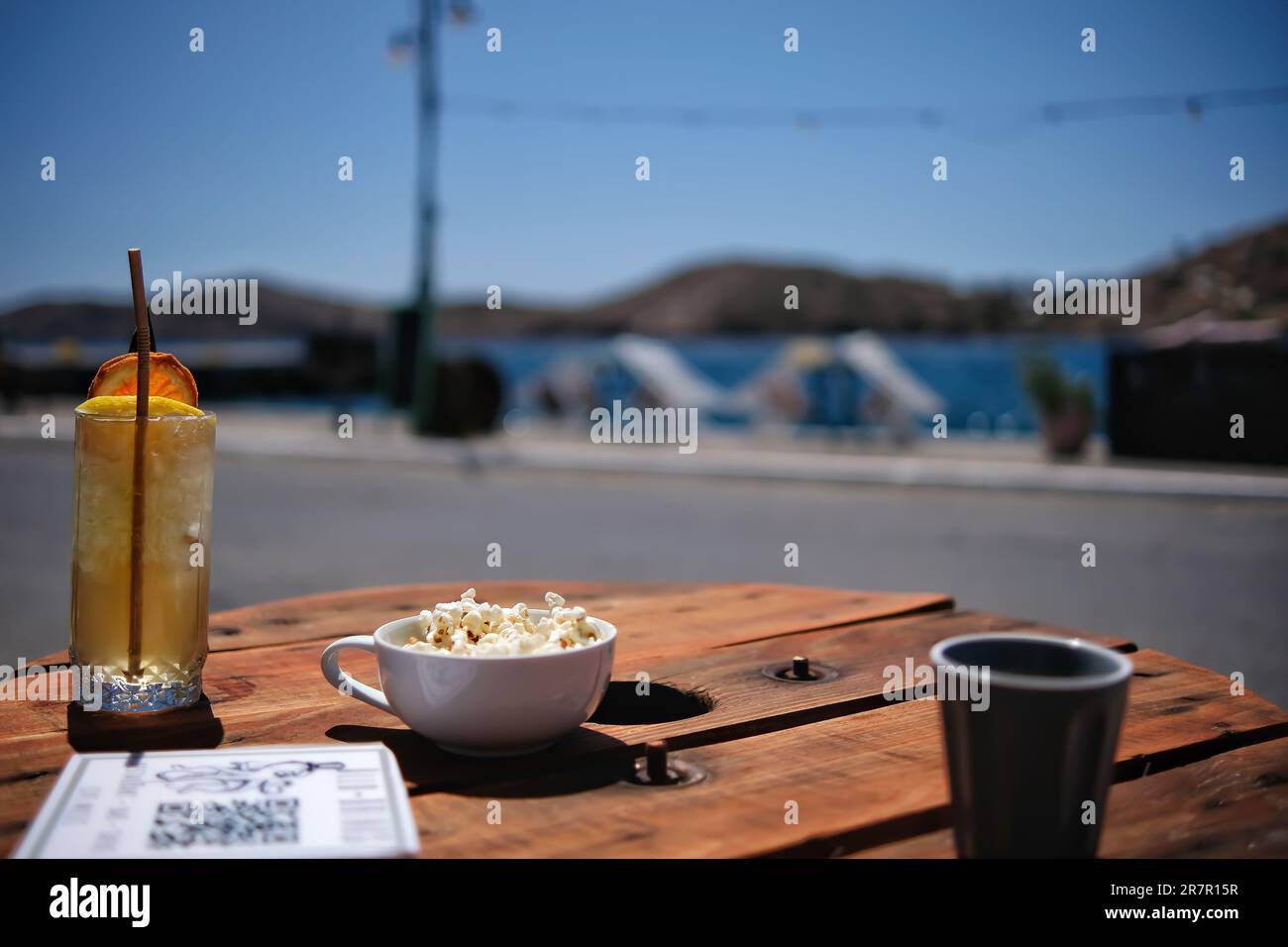 Enjoying a cocktail, a rakomelo and some popcorn in front of the sea in Ios Greece Stock Photo