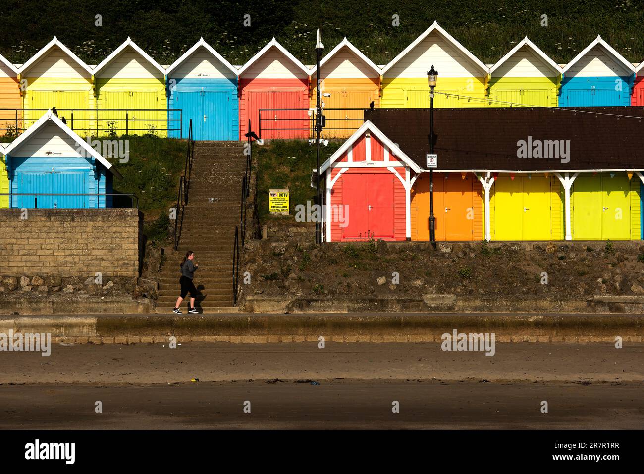 Scarborough, North Yorkshire, UK. 17th June 2023. A jogger soaks up the early morning light in front of the beach huts at North Bay, Scarborough, North Yorkshire. Neil Squires/Alamy Live News Stock Photo