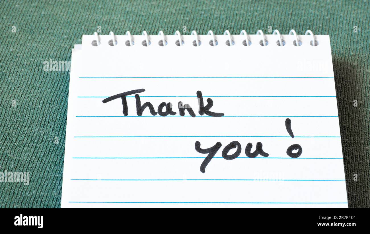 tank you phrase written on white notepad or writing pad with blue lines on green background as gratitude, message, appreciation concept Stock Photo