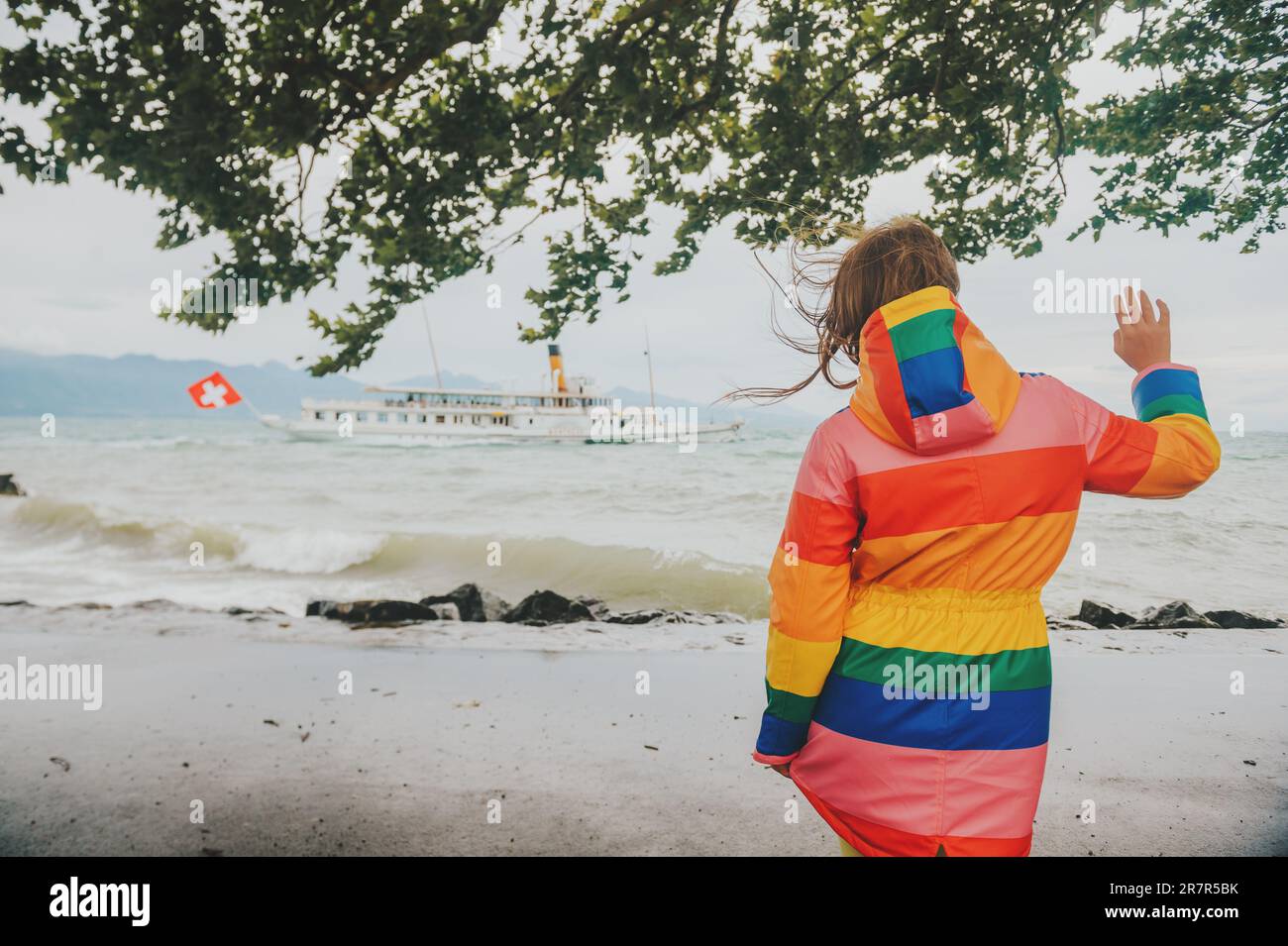 Child waving to sream boat with swiss flag, image taken on lake Geneva, Lausanne, Switzerland Stock Photo