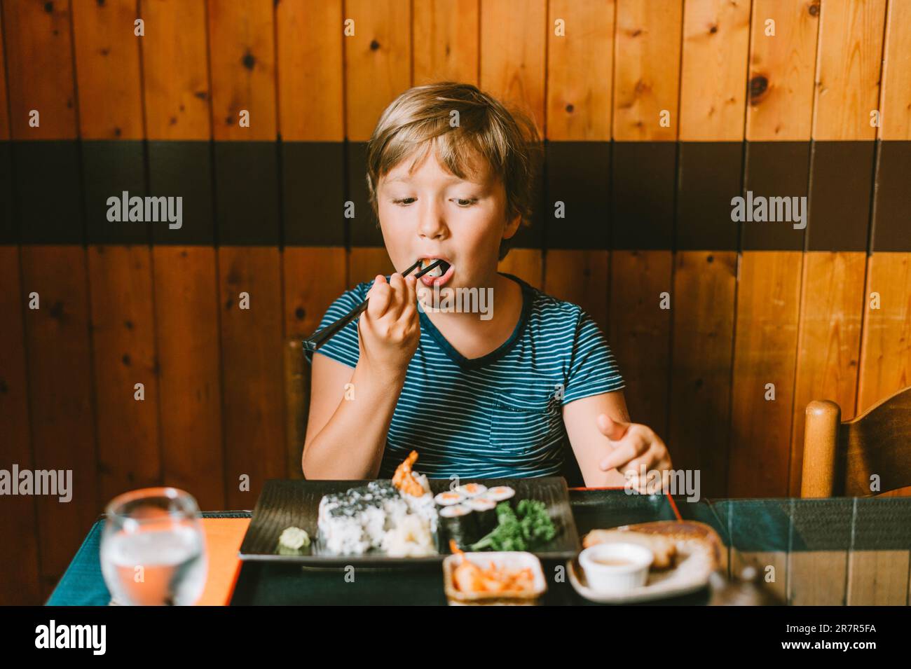 Cute kid boy eating sushi in asian restaurant Stock Photo