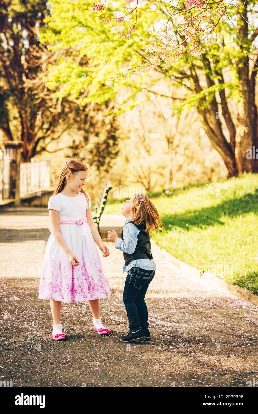 Young girl and boy playing in spring garden, wearing occasion clothes, fashion for young children Stock Photo