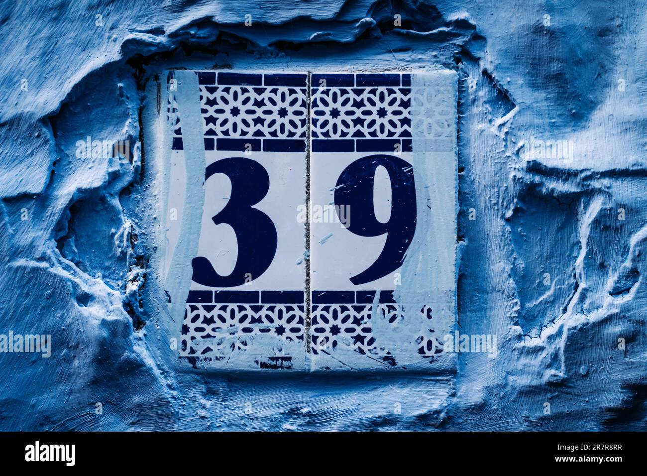 Vibrant blue house post: Numbers adorn this eye-catching house post, creating an intriguing focal point against the vivid blue backdrop. Stock Photo