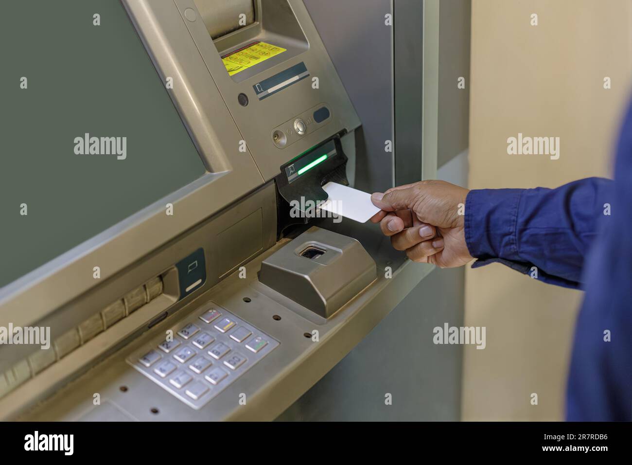 A man's hand inserting a blank card into an ATM. Stock Photo
