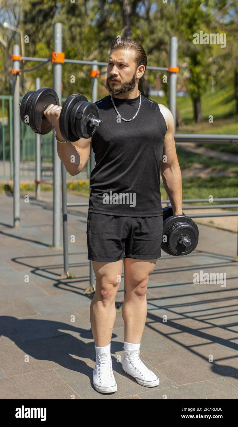 Athletic lebanese man in sportswear doing arms weight lifting dumbbells