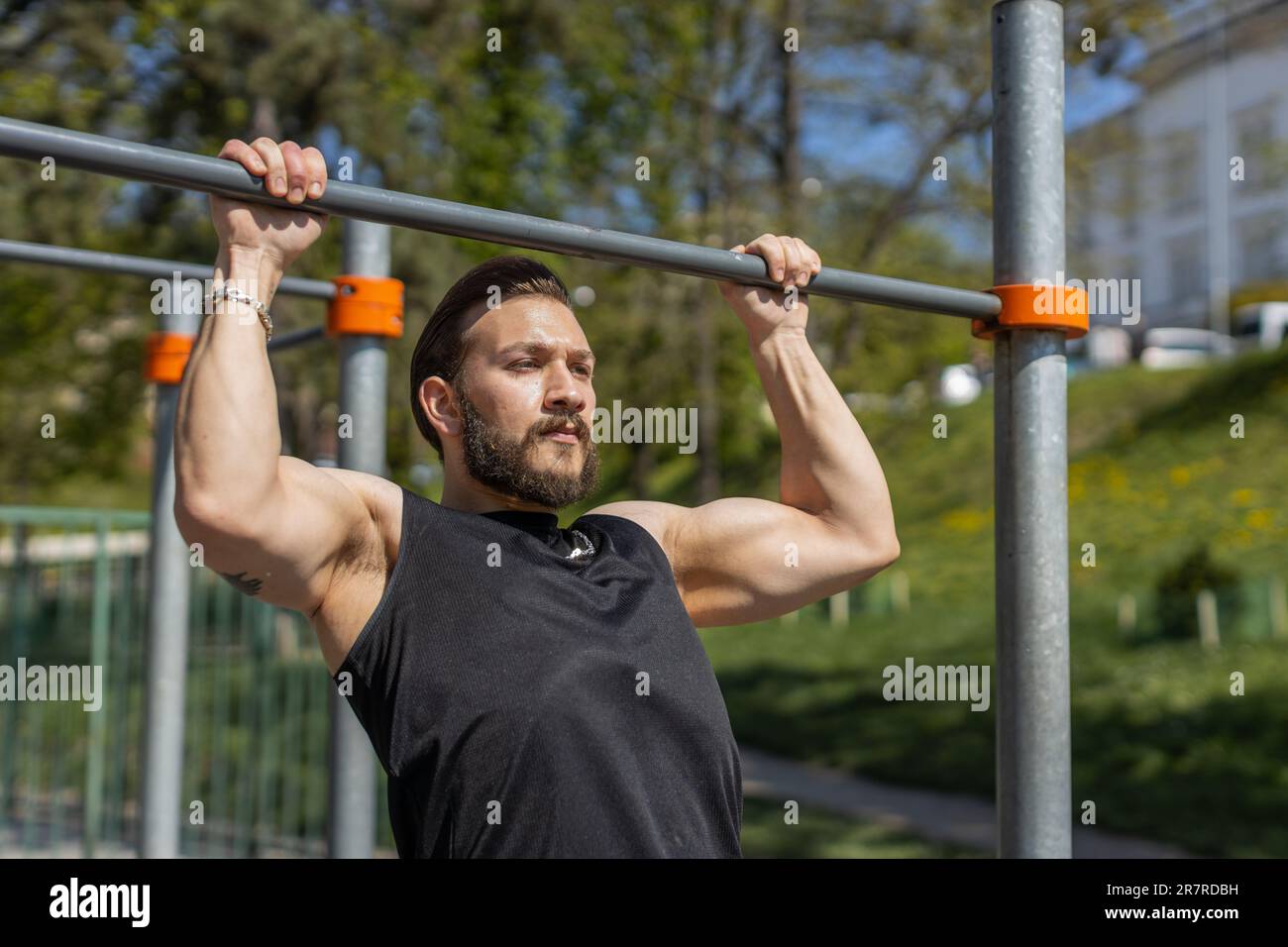 Athletic lebanese man in sportswear doing pull ups exercises on