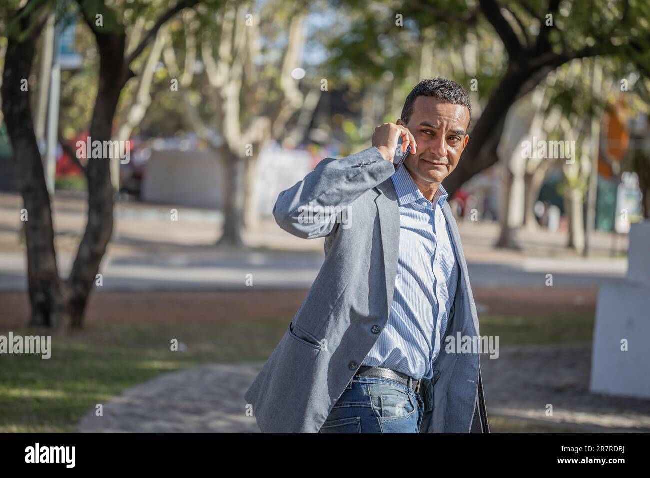 Young latin man in a suit walking in a hurry and talking on the mobile phone. Stock Photo
