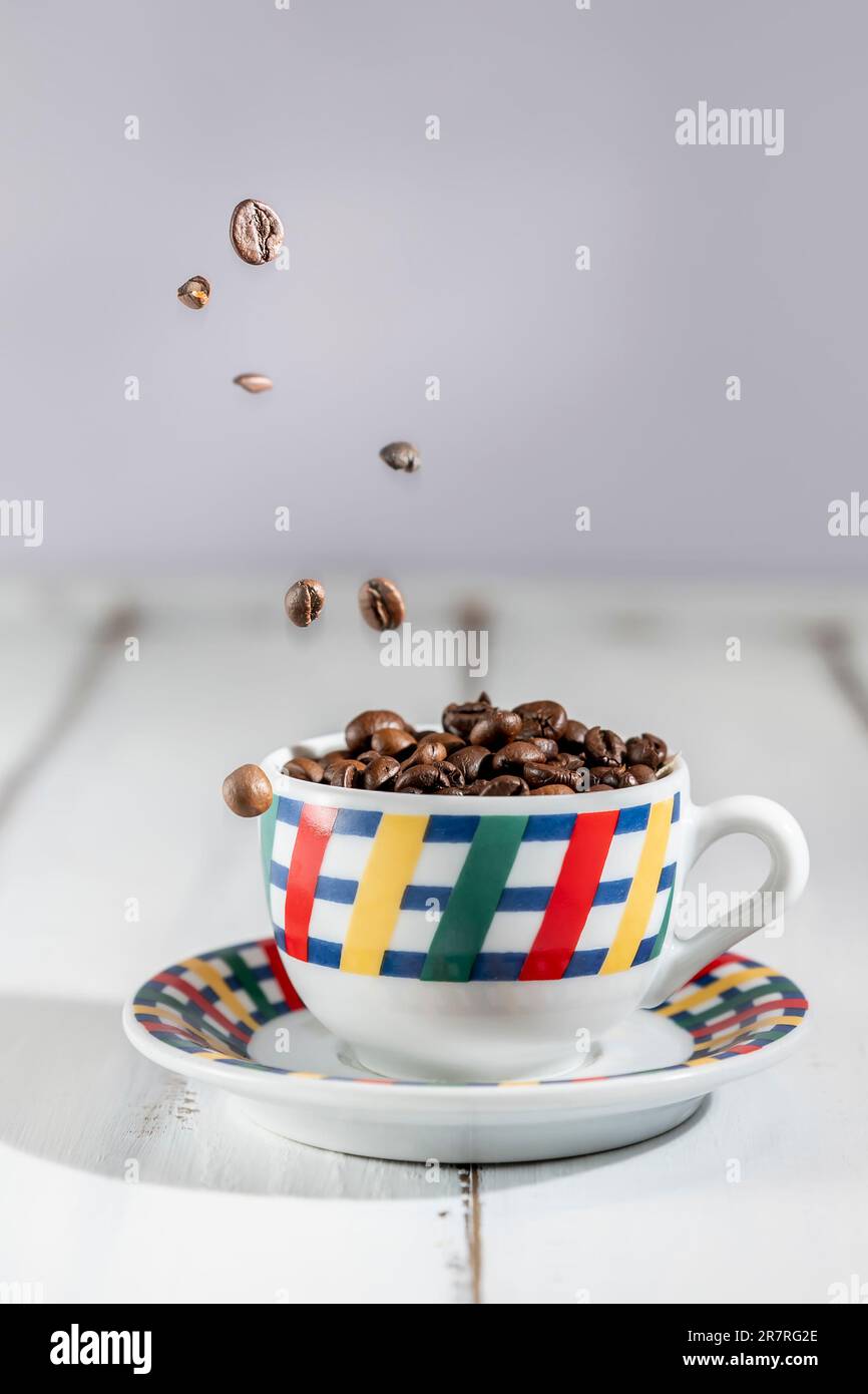 Coffee beans fly into a colorful espresso cup Stock Photo Alamy