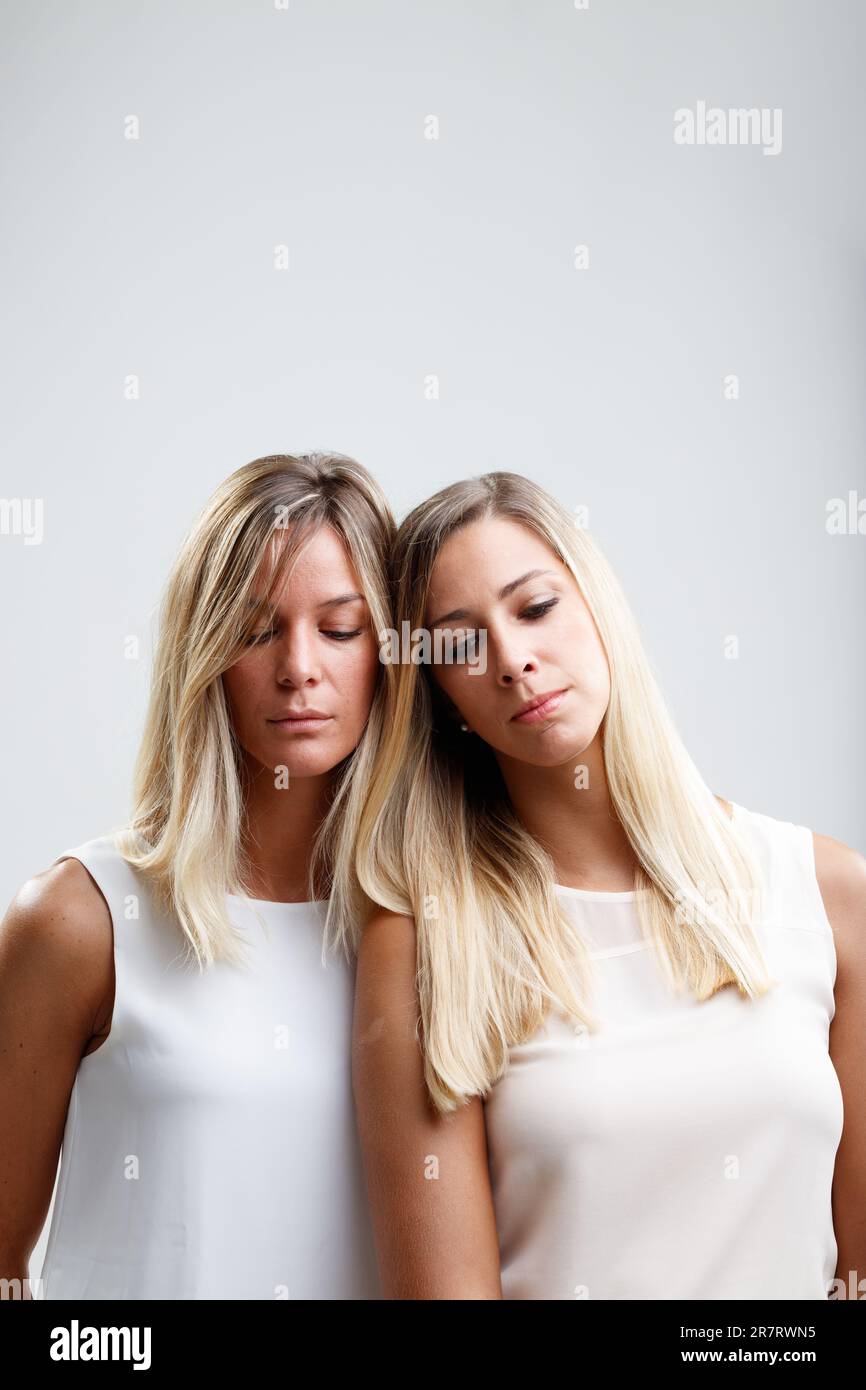Two blondes, leaning on each other, share deeply personal secrets and experiences. Their mutual strength is as notable as their beauty Stock Photo