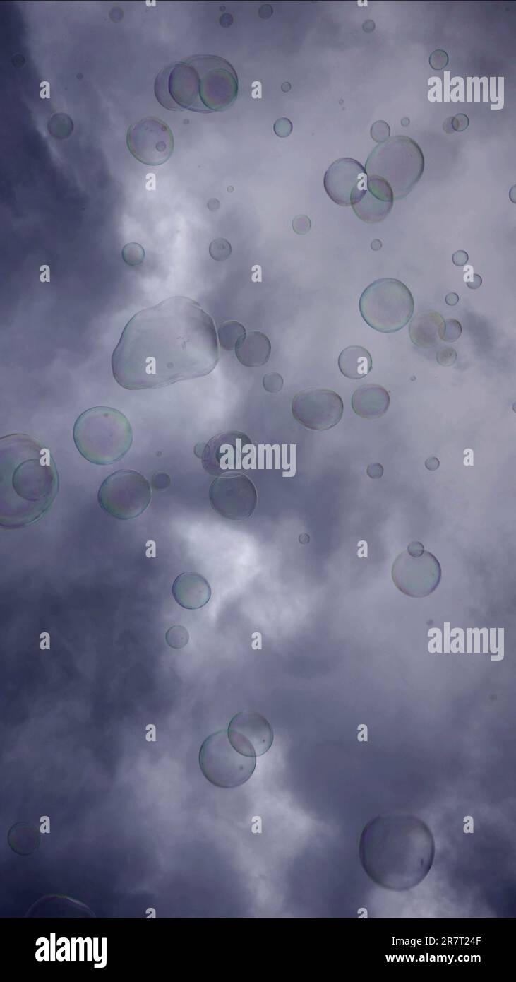 Soap bubbles are flying on gray cloudy sky background Stock Photo