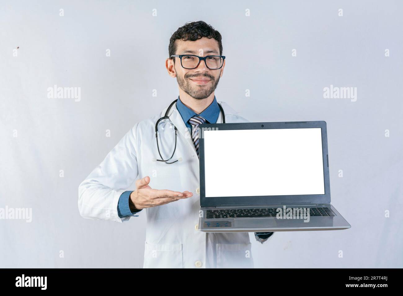 Smiling doctor showing laptop screen isolated. Handsome doctor pointing at laptop screen isolated Stock Photo