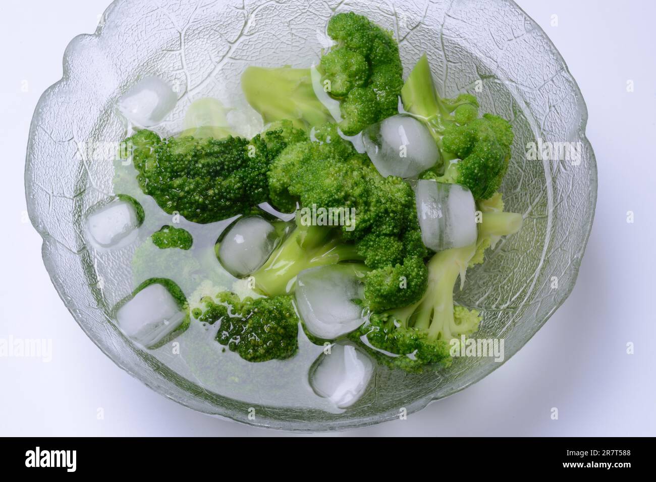 Broccoli, broccoli florets with ice cube cubes in glass bowl, blanching