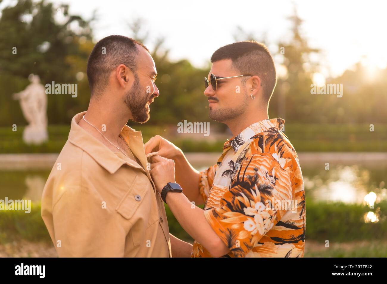 Homosexual couple embracing giving each other a kiss looking at the sunset in a park in the city. Diversity and lgbt concept Stock Photo