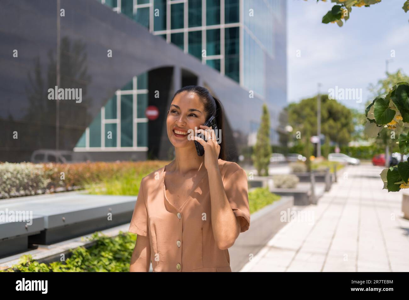 Latin woman executive or businesswoman in a business office area leaving work talking on the phone Stock Photo