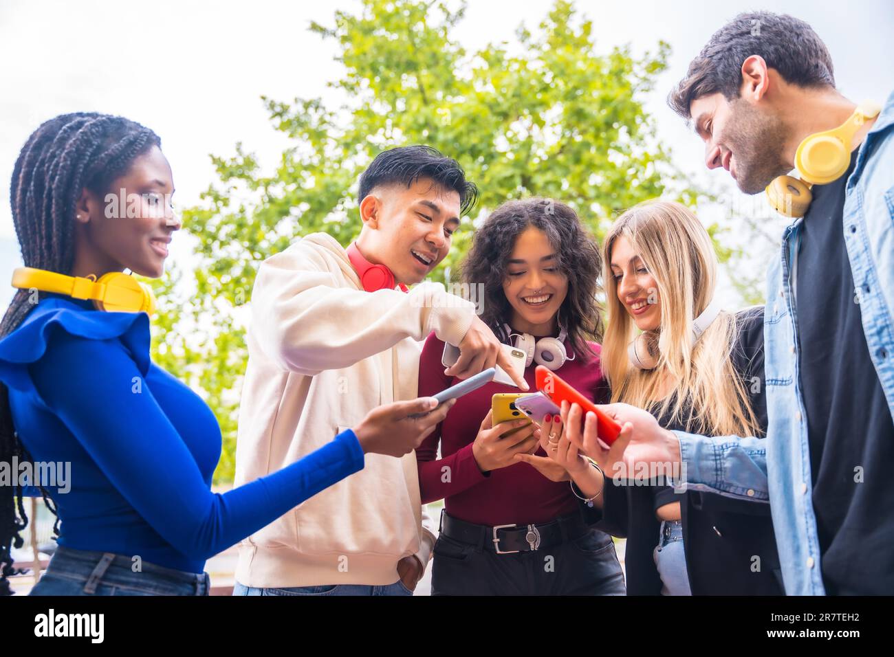 A group of young multi-ethnic teenage friends using cell phones in the ...