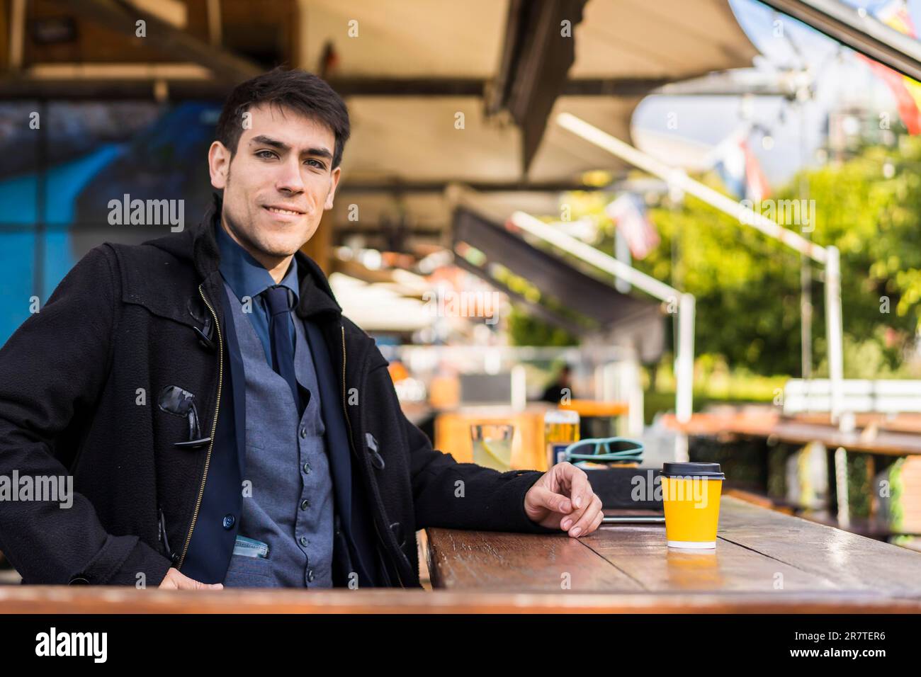 Handsome man looking at camera while smiling after drinking a coffee at a bar Stock Photo