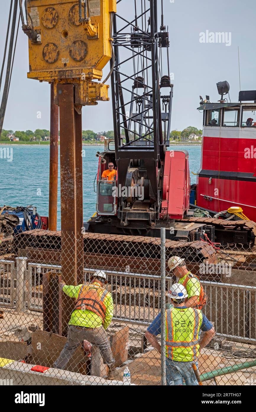 Detroit, Michigan, Workers repair the seawall along the Detroit Riverwalk using a pile driver mounted on a barge on the Detroit River Stock Photo