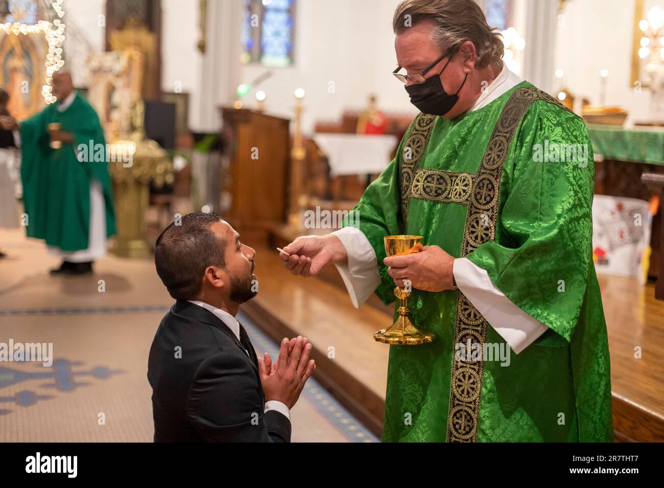 Detroit, Michigan, Msgr. Charles Kosanke gives communion at a mass at Holy Trinity Catholic Church in support of immigrants around the world. The Stock Photo