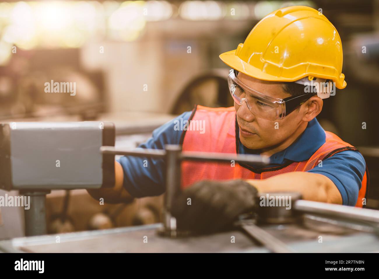 Male mechanic worker with safety helmet working labor in metal industry factory with steel machining. Stock Photo
