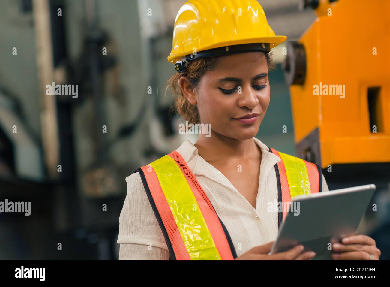 Happy African American Woman Engineer Worker Supervisor looking at Tablet computer to control operate maching in Heavy Industry Factory. Stock Photo