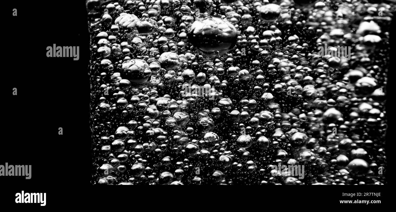 Soda water bubbles splashing underwater against black background. Cola
