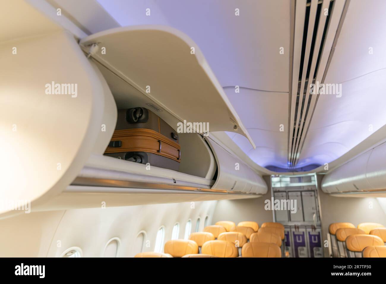 In flight carry on bag cabinet, on board suitcase storage overhead bin in passenger cabin crew. Stock Photo