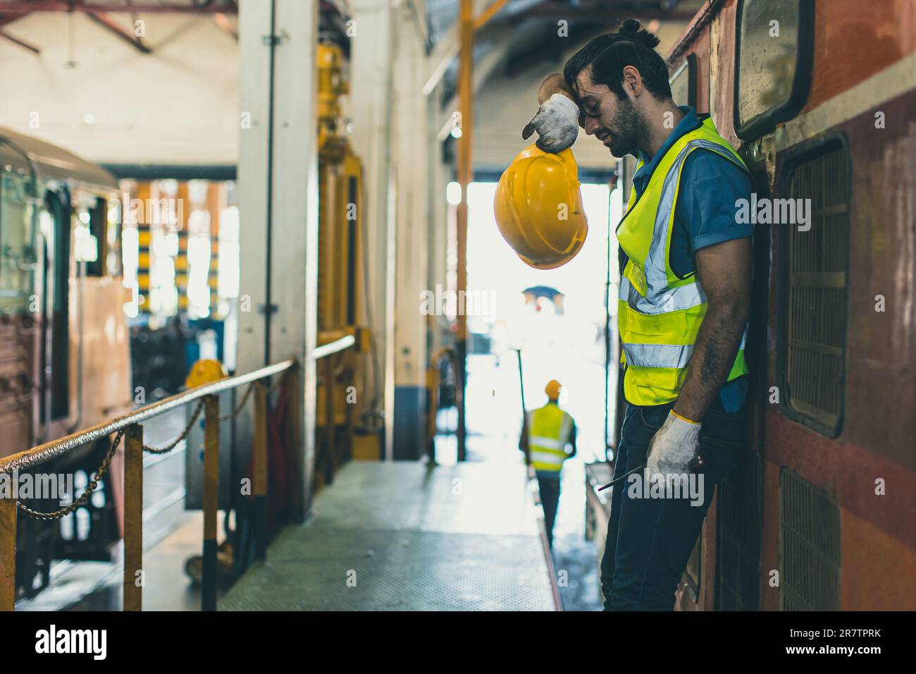 Tired exhausted worker hard work, Locomotive engineer mechanic staff feel fatigue work in train repair shop service station dirty hot workplace machin Stock Photo