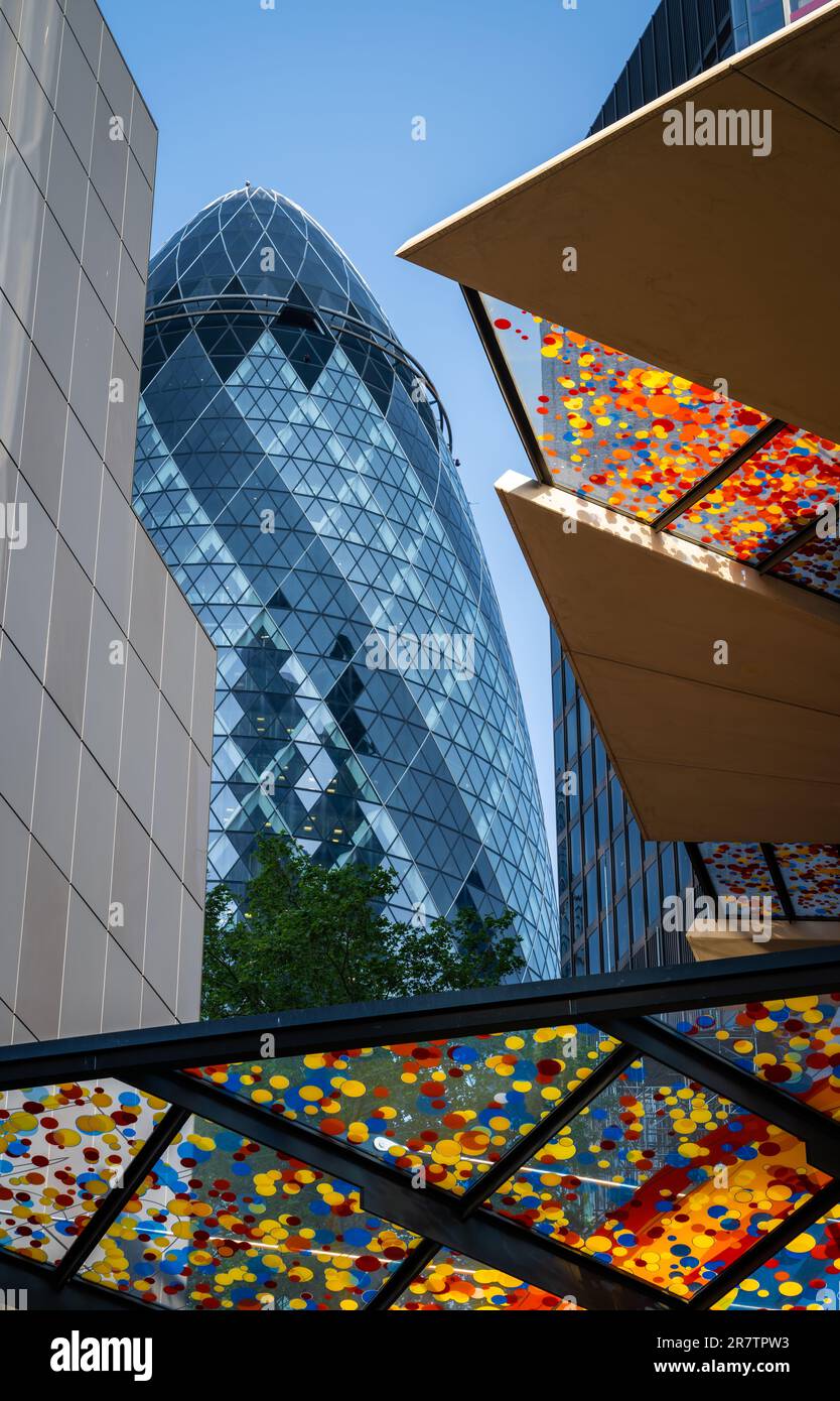 London, UK:  The Gherkin skyscraper in the City of London with the colorful canopy above the entrance to 22 Bishopsgate in front. Stock Photo