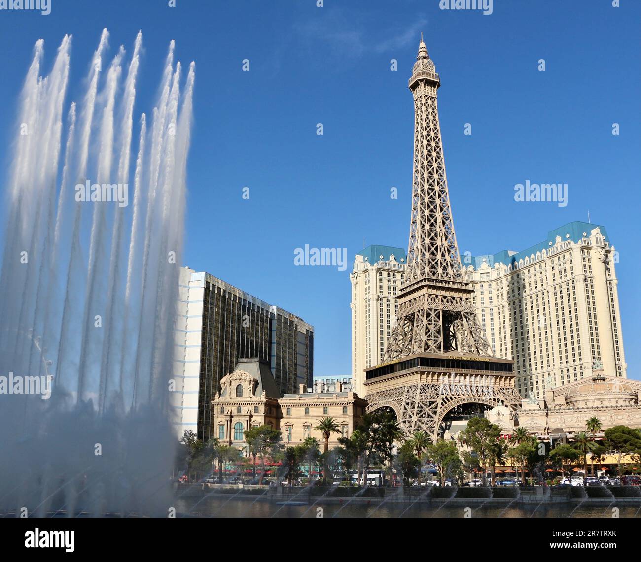 Bellagio resort fountains during a display with the fake half scale Eiffel Tower at the Paris casino and resort in afternoon sun Las Vegas Nevada USA Stock Photo
