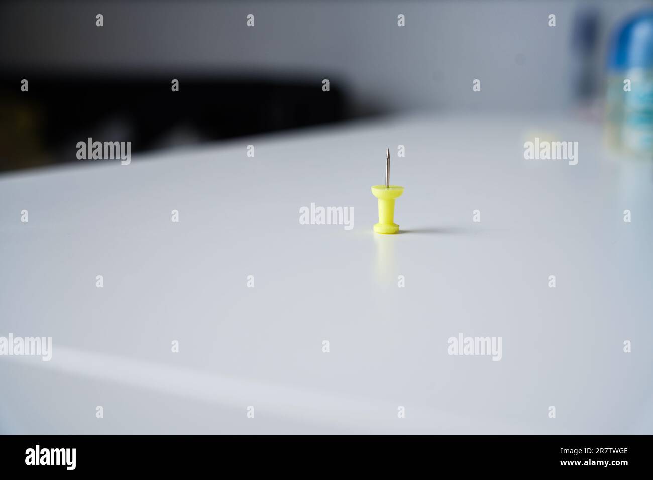 One yellow pin stands alone on a white background table with space for