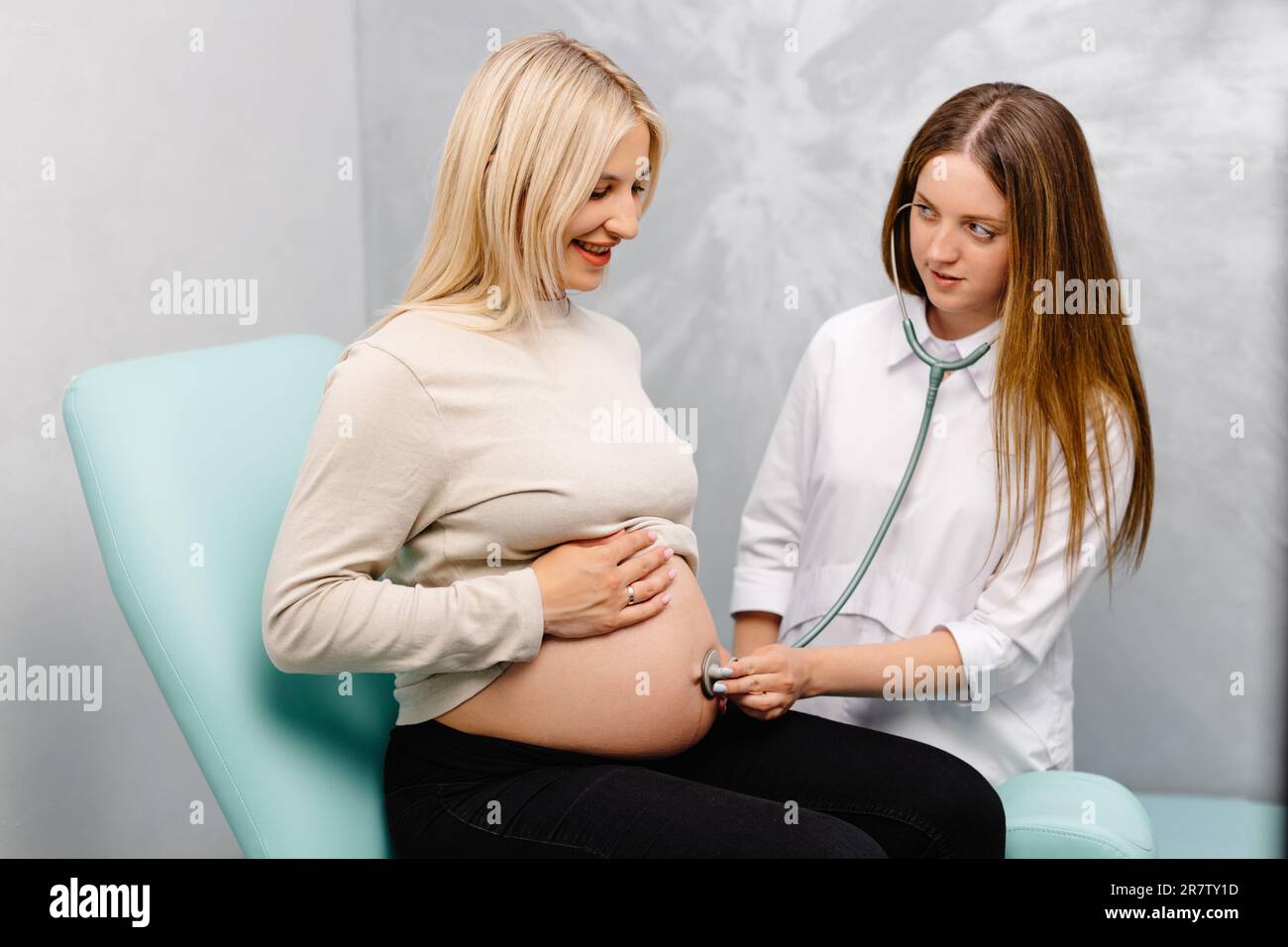 Female doctor using stethoscope examining pregnant woman in clinic