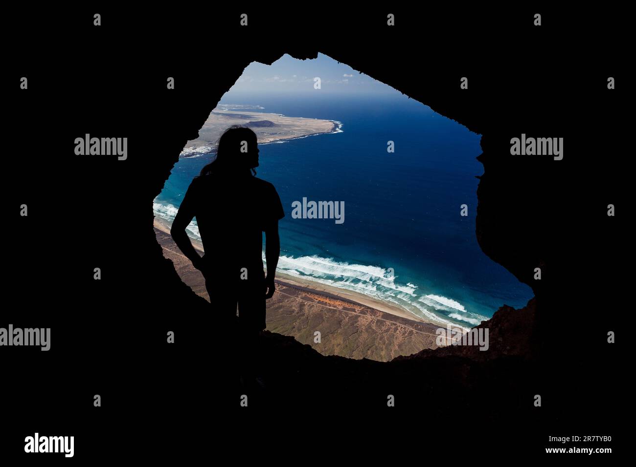 A young man overlooking the Atlantic Ocean from the cliffs of Famara, on the island of Lanzarote, Canary Islands in Spain. Stock Photo