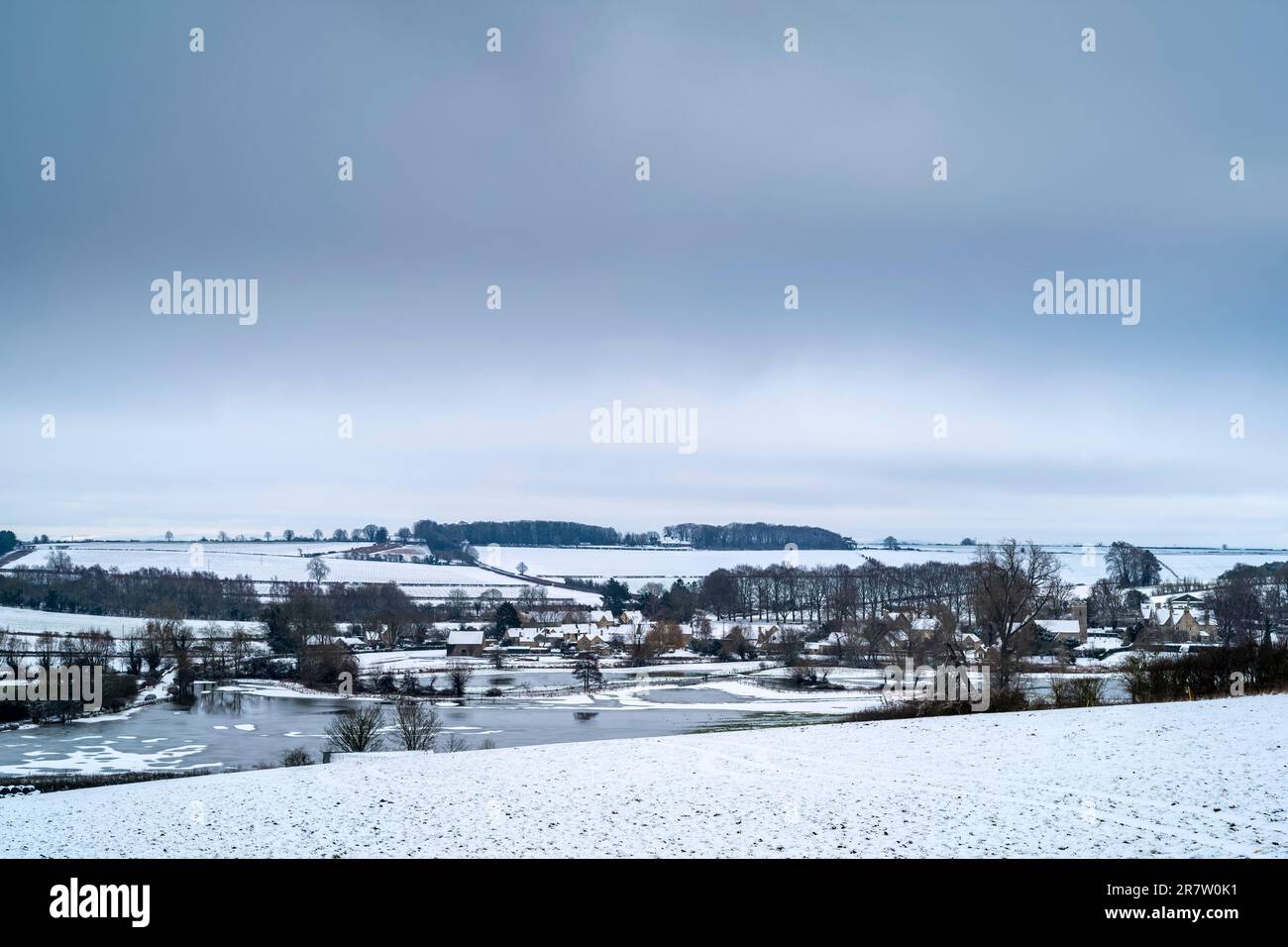 Picturesque snow-covered field and wintry scene at Asthall village in The Cotswolds, Oxfordshire Stock Photo