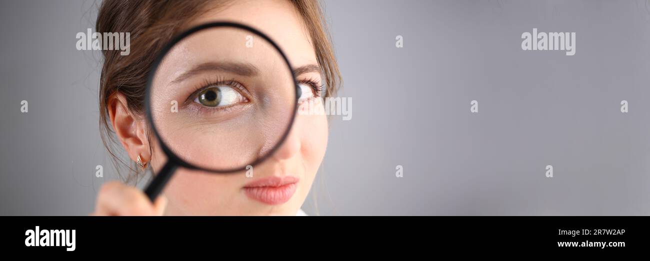 Inquisitive young woman looking through magnifying glass Stock Photo ...