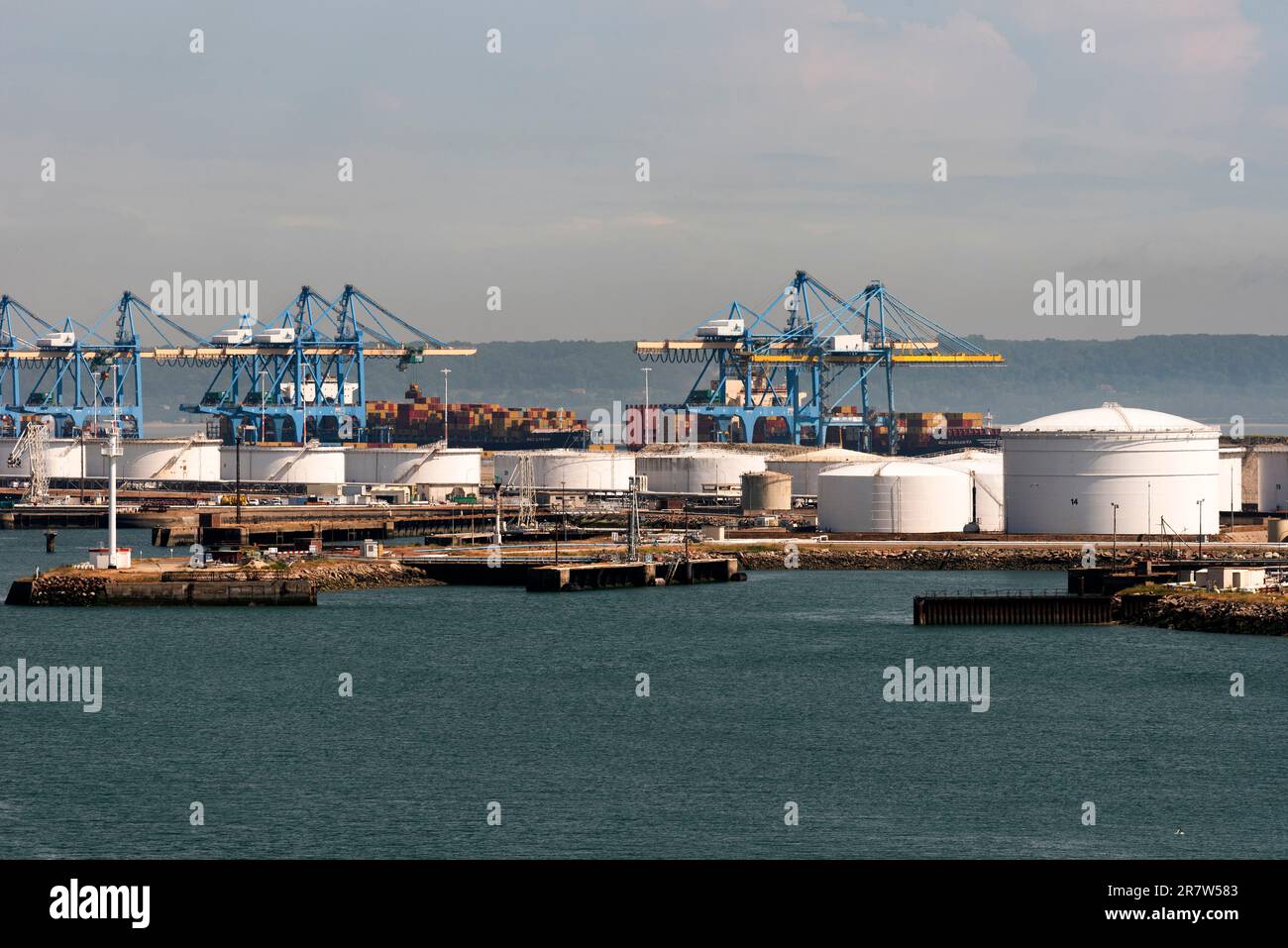 Le Havre, northern France, Europe. 2023. Cranes in the container port and storage  tanks alongside a jetty in the Port of Le Havre, France. Stock Photo