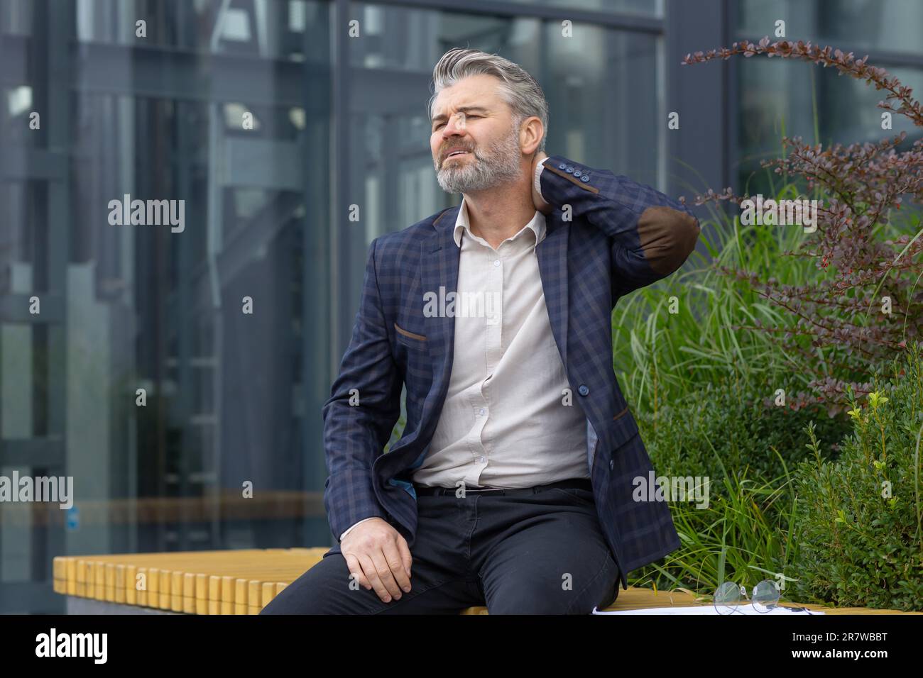 Overtired mature man resting on bench outside office building after ...