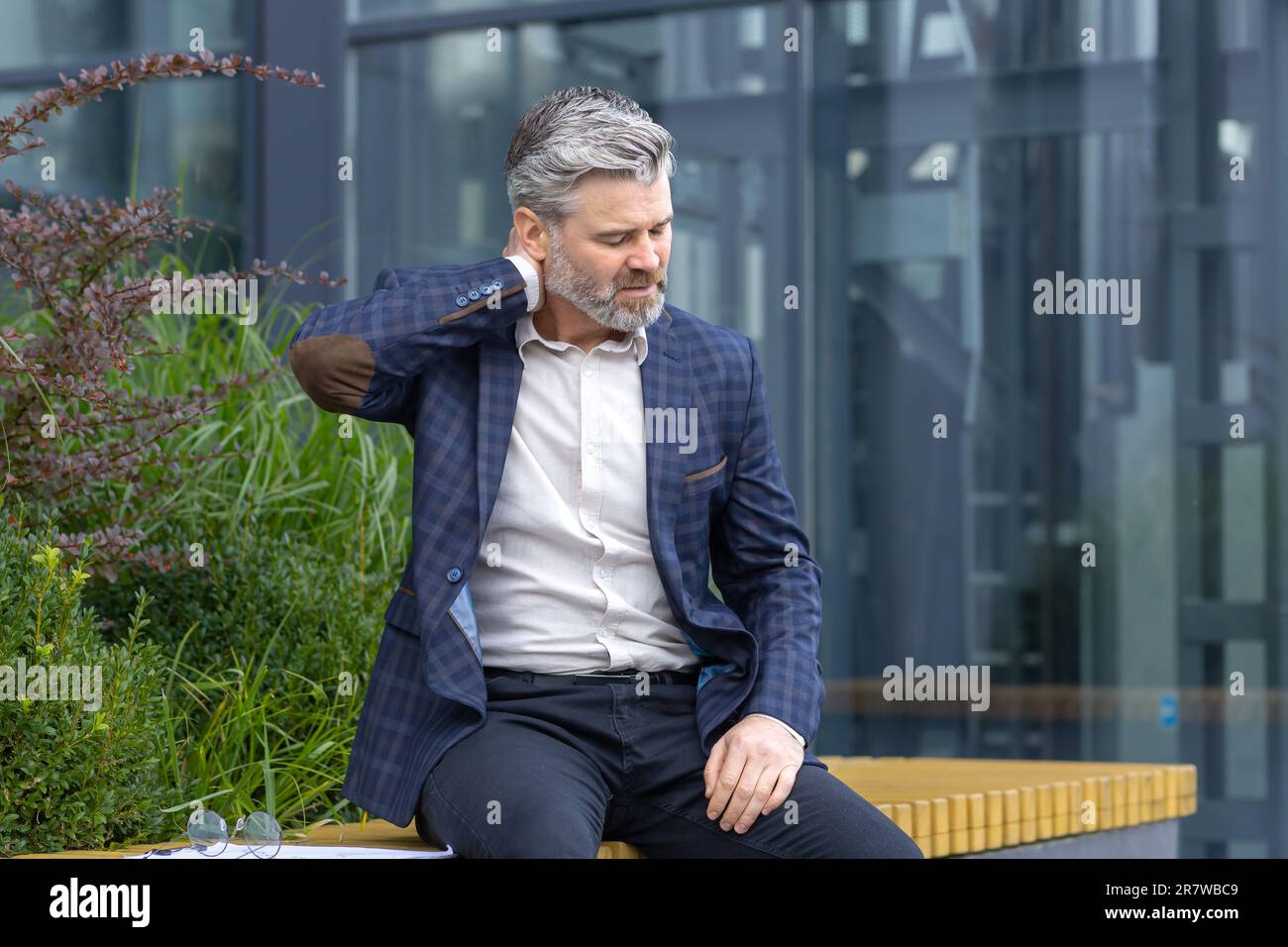 Overtired mature man resting on bench outside office building after ...