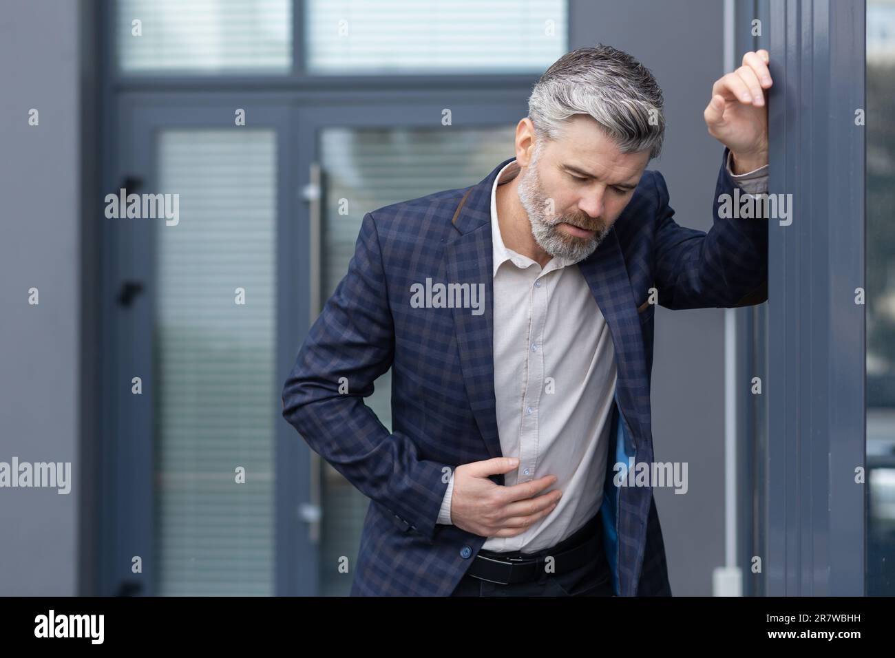 Mature gray haired boss has food poisoning, man outside office building ...
