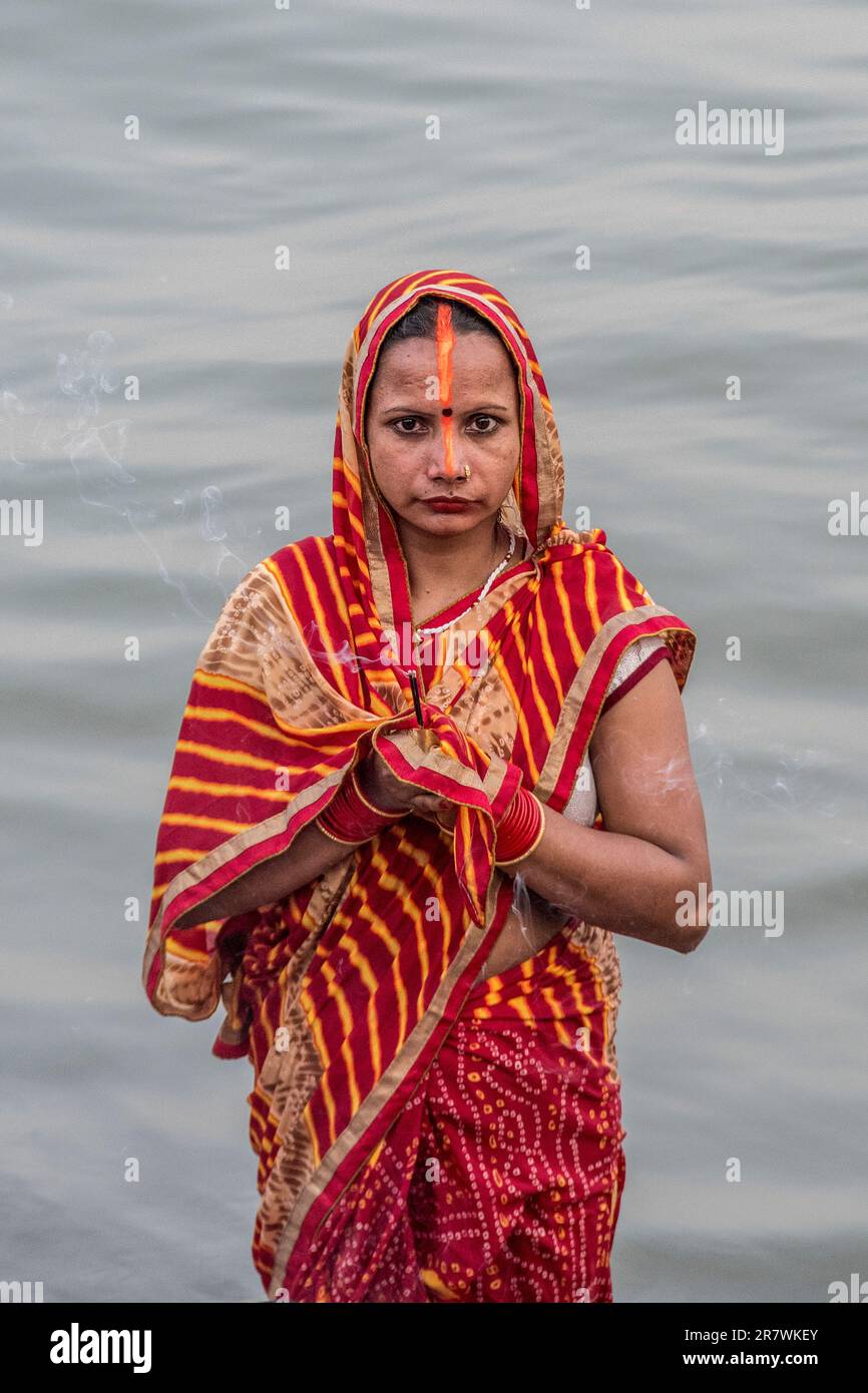 A devotee makes an offering and prays in the Ganges during Chhath Puja ...