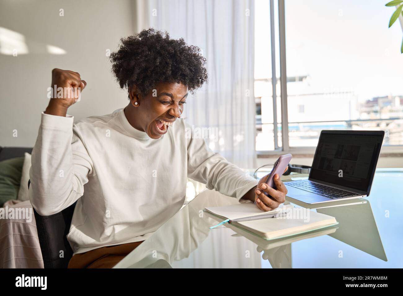 Happy African American teen student feeling excited holding mobile ...