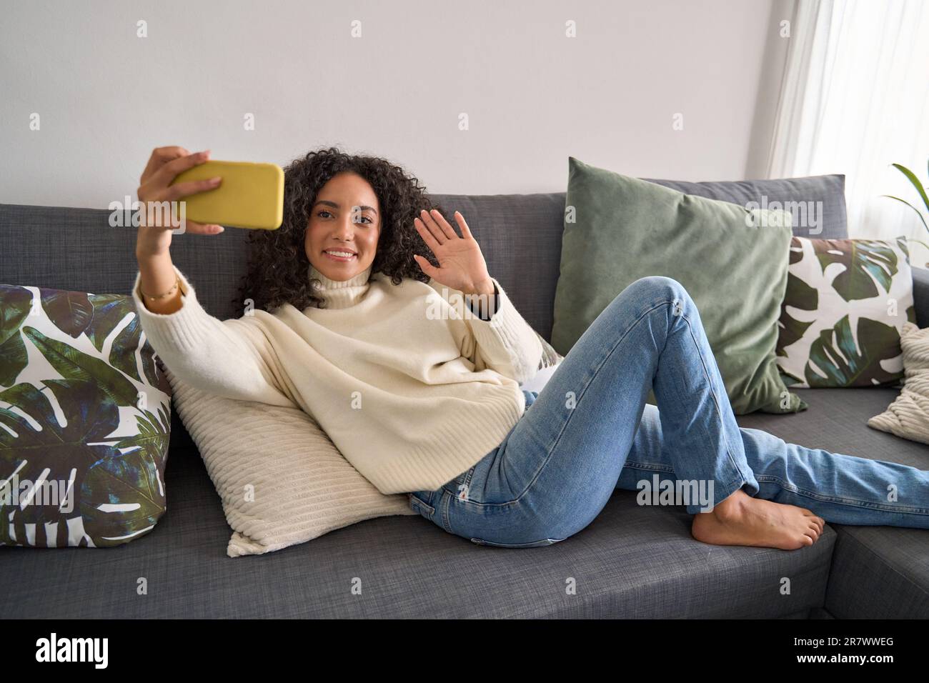 Happy latin girl sitting on couch using mobile cell phone at home Stock ...