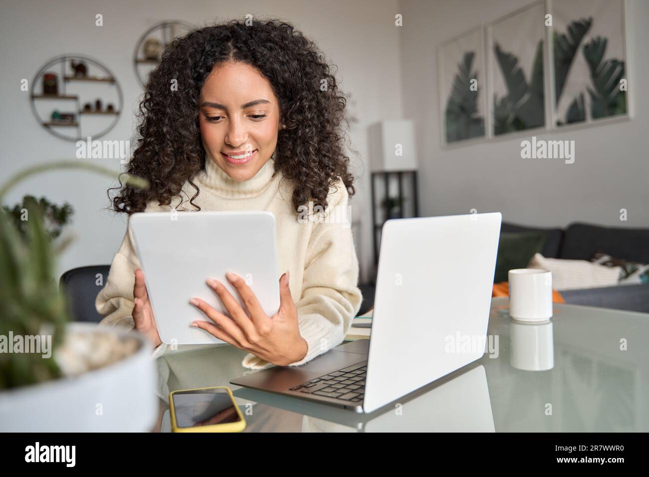 Smiling latin girl student using digital tablet elearning at home. Stock Photo