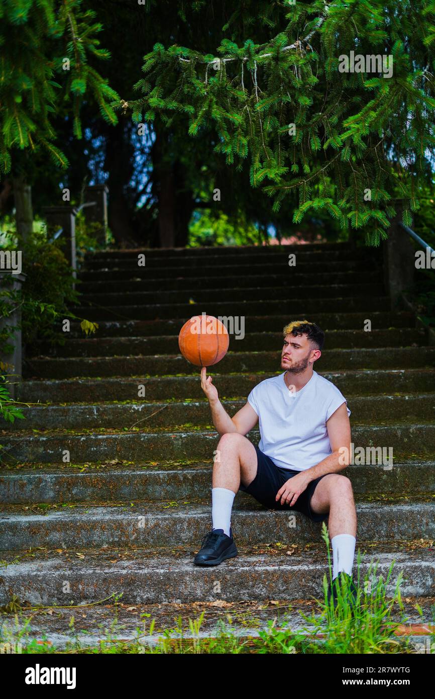Basketball player posing with a basket ball spinning the ball on his finger  in a beautiful spot with vegetation Stock Photo - Alamy