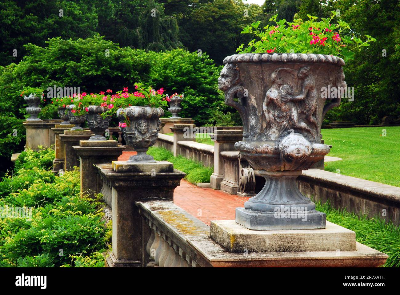 Grecian urns hold pretty flowers in a formal garden on an estate grounds in Long Island Stock Photo