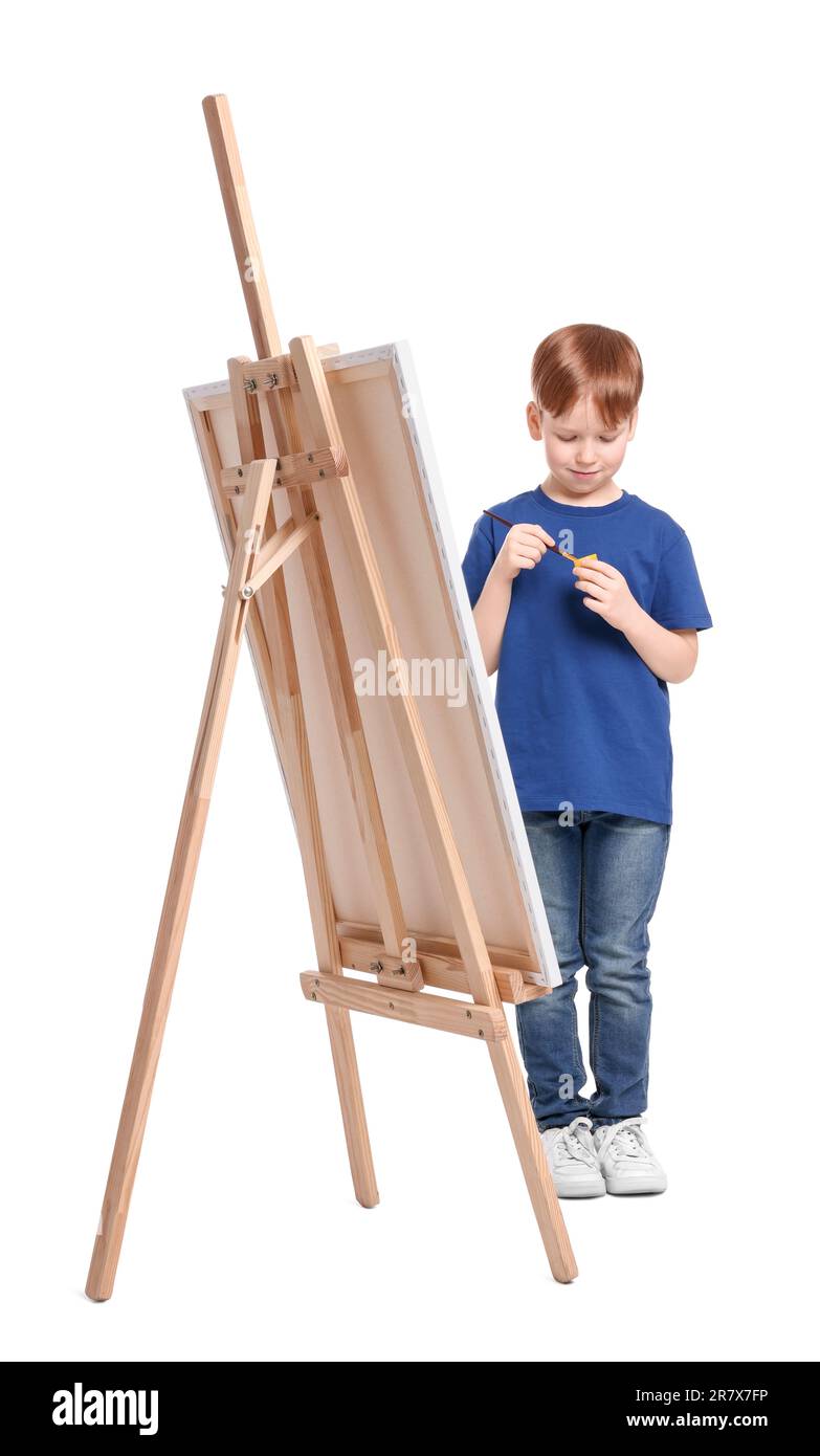Little boy painting against white background. Using easel to hold ...