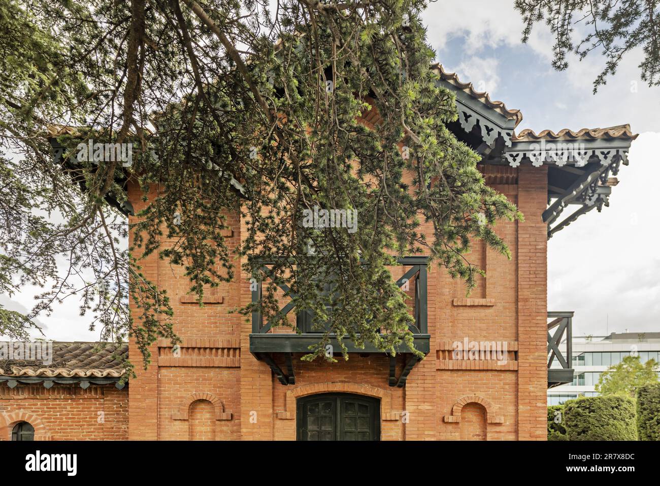 Facade of a vintage brick building with green balconies, gables on the roofs and pine branches in front Stock Photo